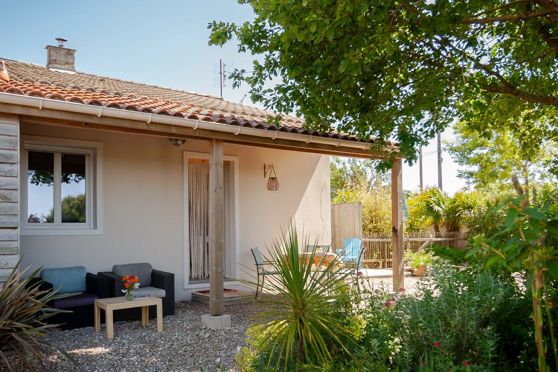 Overdekt terras met loungestoelen en grote bloementuin